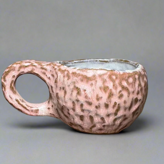 Ceramic pot with a handle on a wooden surface against a gray background